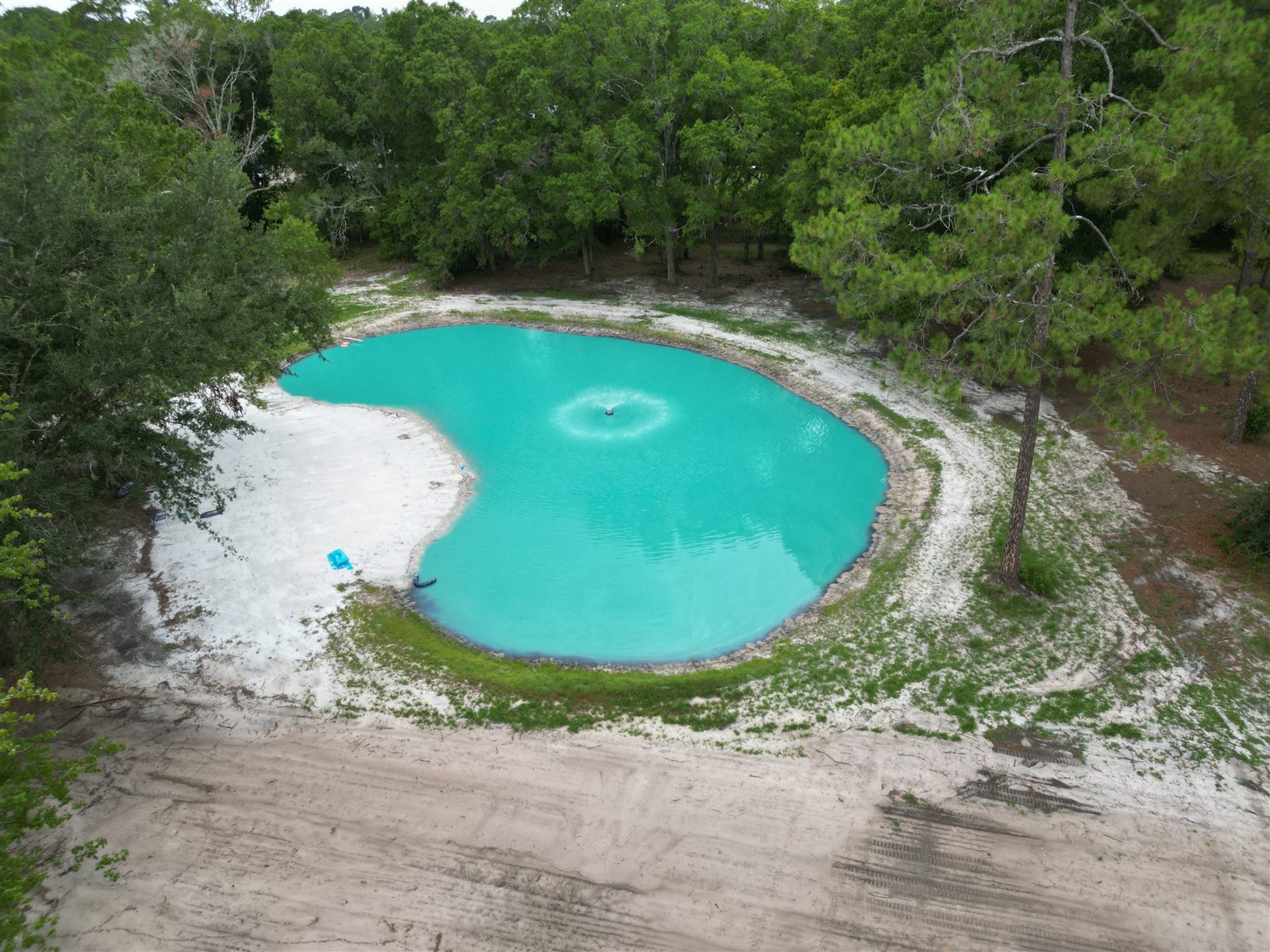 Finished pond with fountain and sand beach built by Triple H Excavation